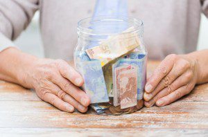 A person holding onto some money in a jar